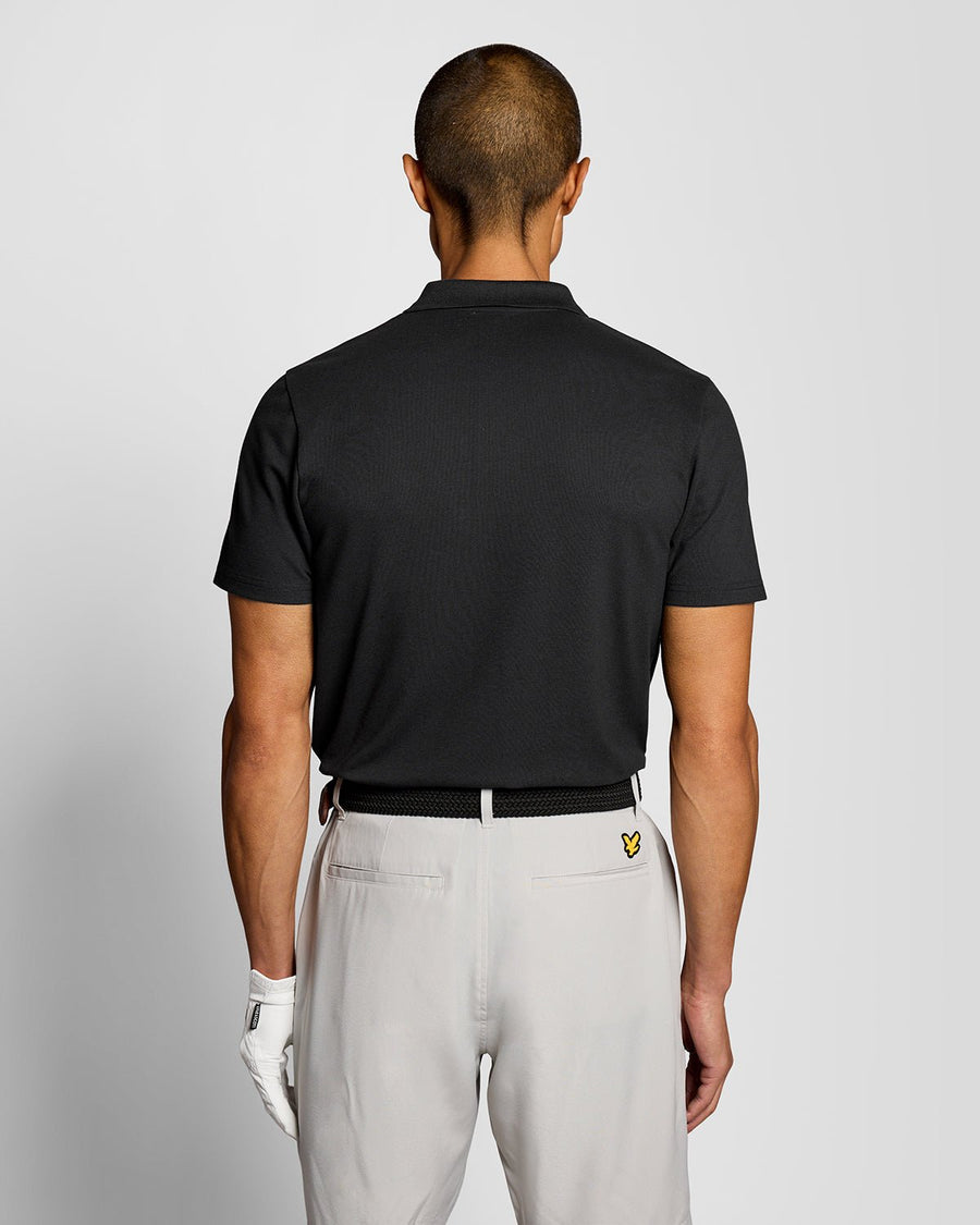 Un homme porte un polo technique noir de jais