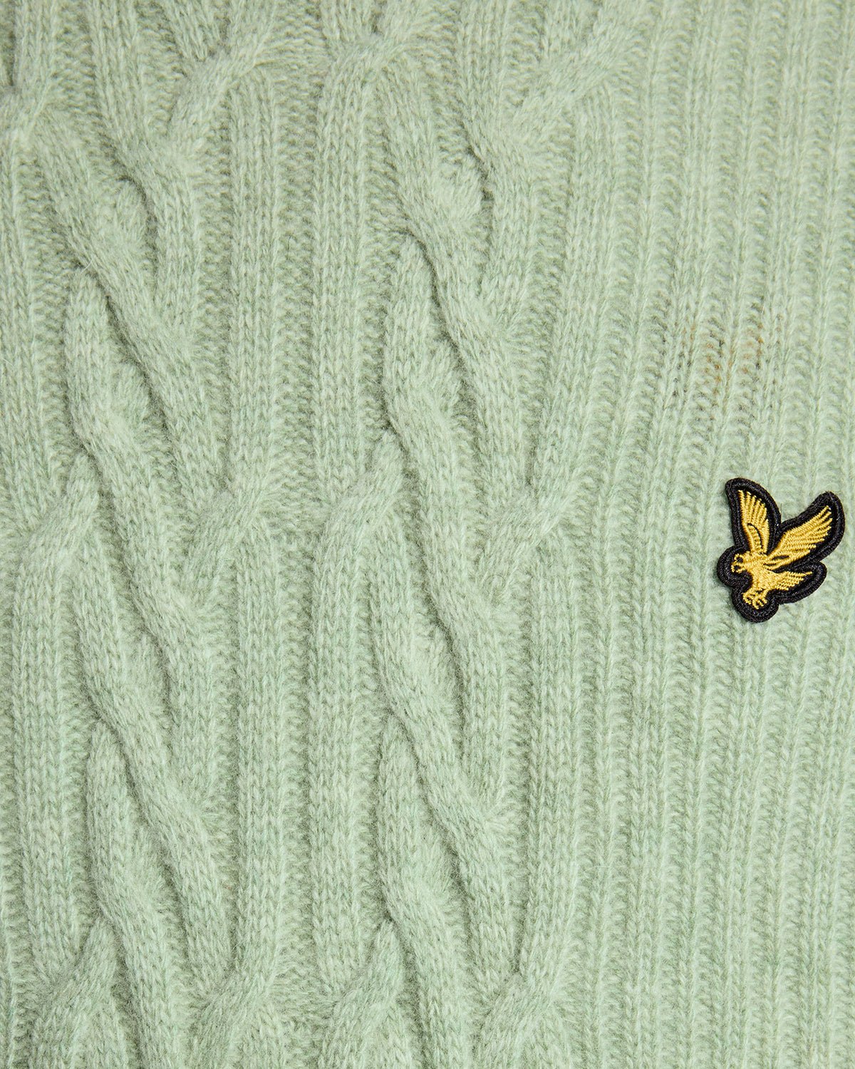 Un homme porte un pull en maille torsadée côtelée, couleur « Cold Mint Marl »