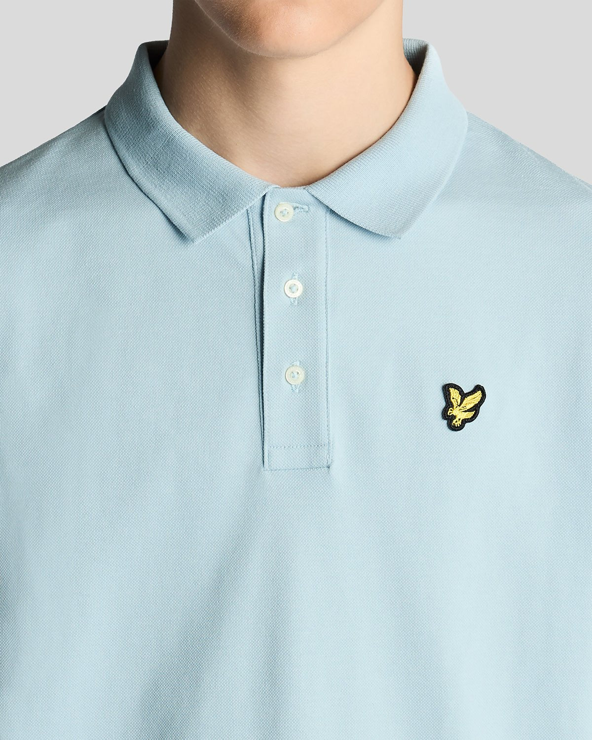 Un homme porte un polo en coton bleu opale