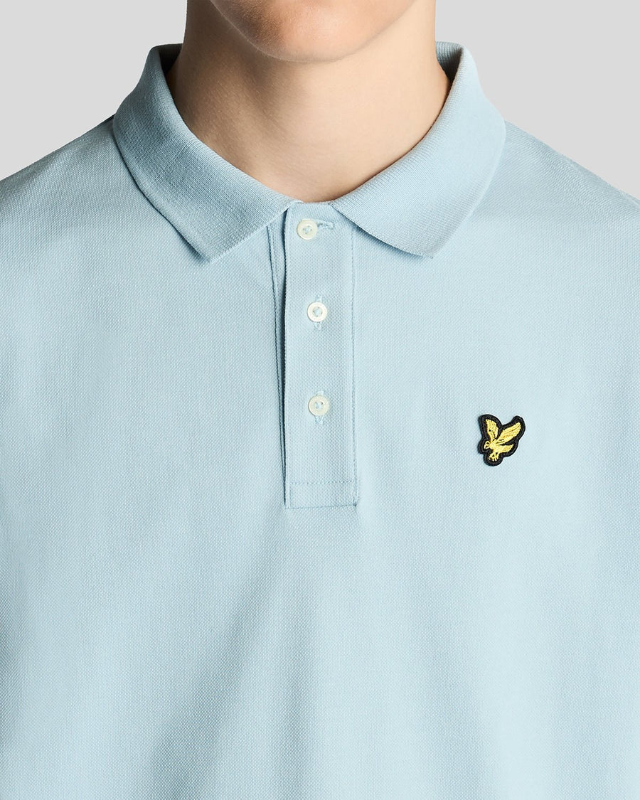 Un homme porte un polo en coton bleu opale