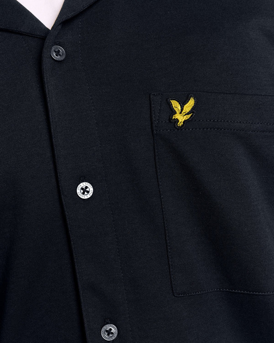 Un homme porte une chemise à manches courtes et col revers, de couleur bleu marine foncé