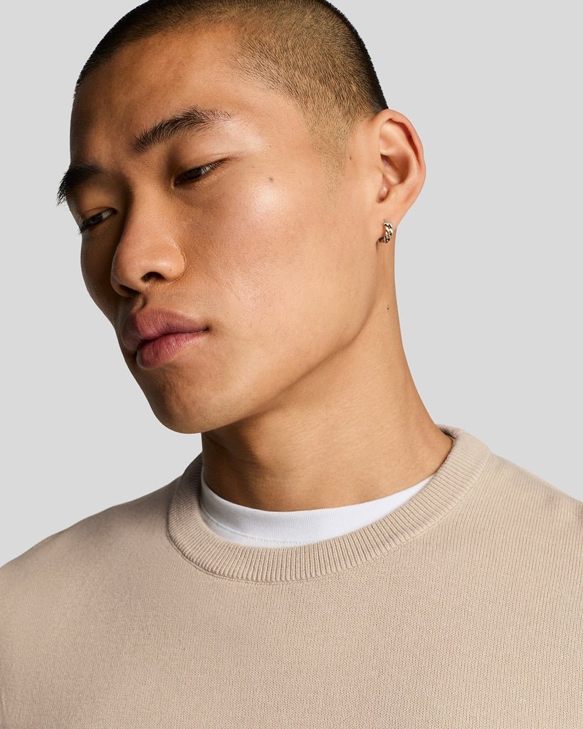 Un homme porte un pull à col rond en coton, couleur Cove