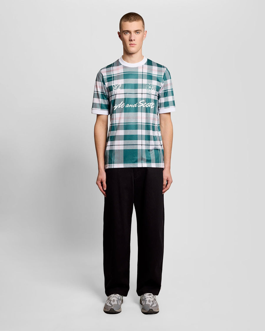 Un homme porte un maillot de football à carreaux tartan de sport, couleur Everglade