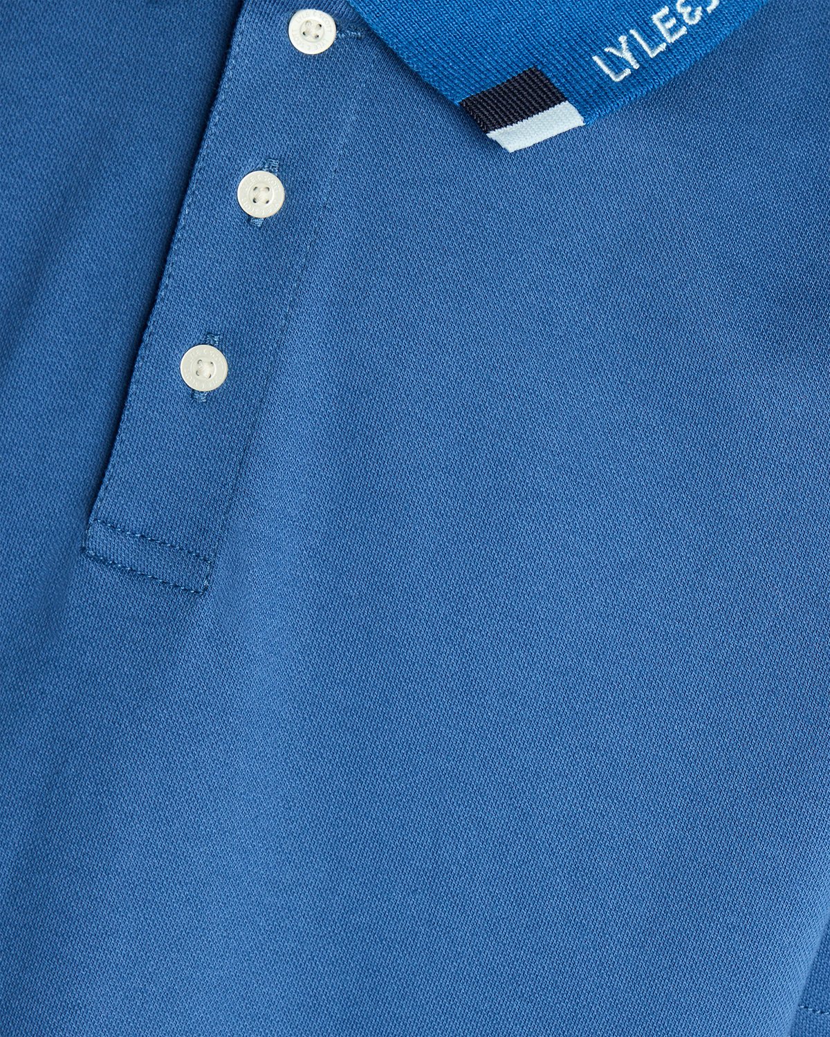 Un homme porte un polo à logo bicolore bleu barbeau foncé