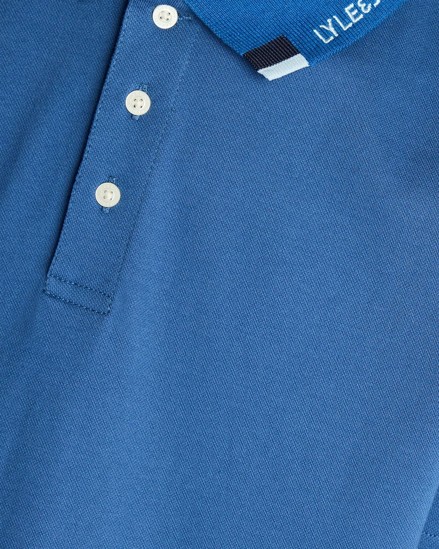 Un homme porte un polo à logo bicolore bleu barbeau foncé