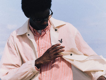Man wearing a translucent jacket with shirt underneath, staring at the black eagle logo under a blue sky